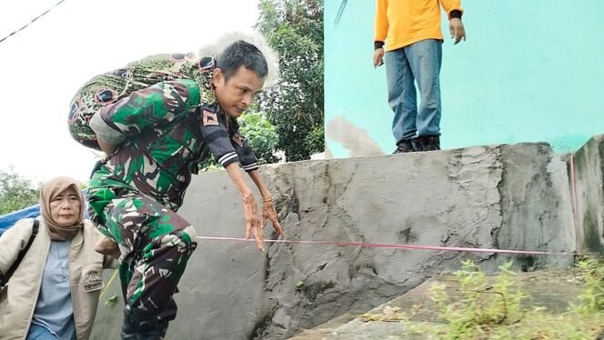 
					Babinsa Sertu Taufik Hadi Gendong Korban Tanah Longsor, Rabu (27/12/23).
