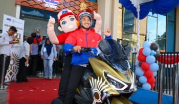 Kurir dan maskot JNE di atas motor operasional siap mengantar paket.