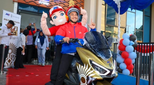 Kurir dan maskot JNE di atas motor operasional siap mengantar paket.