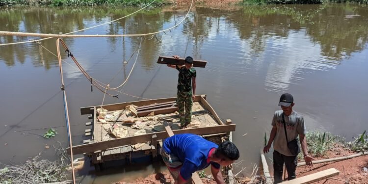 Personel Kodim 0914/TNT dan Warga Gotong Royong Seberangkan Material Besi