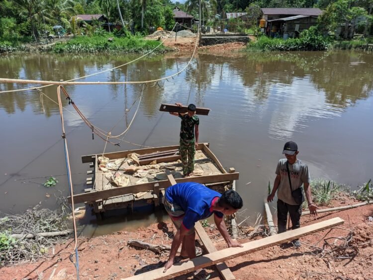 Personel Kodim 0914/TNT dan Warga Gotong Royong Seberangkan Material Besi